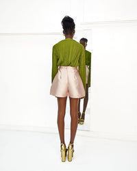 The back of A model wearing an Olive top and Nude colored shorts in a white room