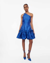A model wearing a one-shoulder blue dress with drop waist ruffle detailing