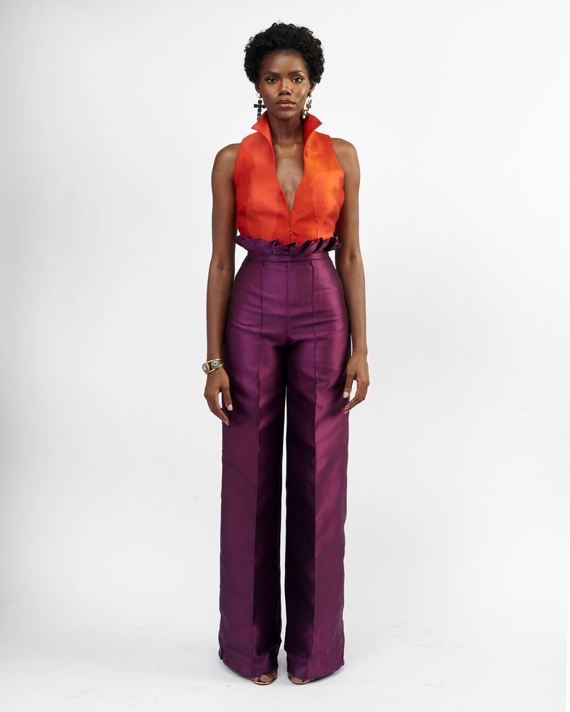 A model wearing purple silk satin pants with an orange top 