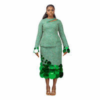 A model wearing a Green top with cut-out neckline detail and sequins embellishment at the neckline and sleeve hem and a Green midi skirt with sequins embellishment