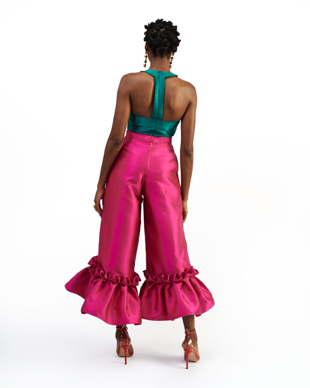The back of a model wearing a green silk satin top and magenta silk satin pants with ruffle hem culottes
