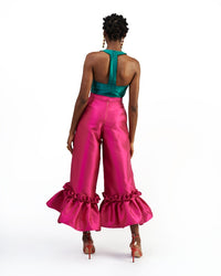 The back of a model wearing a green silk satin top and magenta silk satin pants with ruffle hem culottes