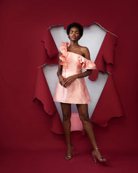 A model wearing a peach colored dress in a red room