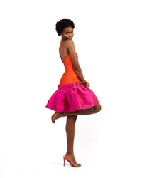 The side of a model wearing an orange and magenta silk satin dress