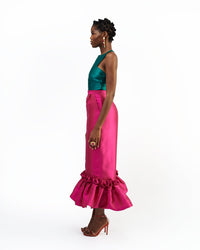 The side of a model wearing a green silk satin top and magenta silk satin pants with ruffle hem culottes
