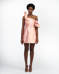 A model wearing a peach colored dress in a white room
