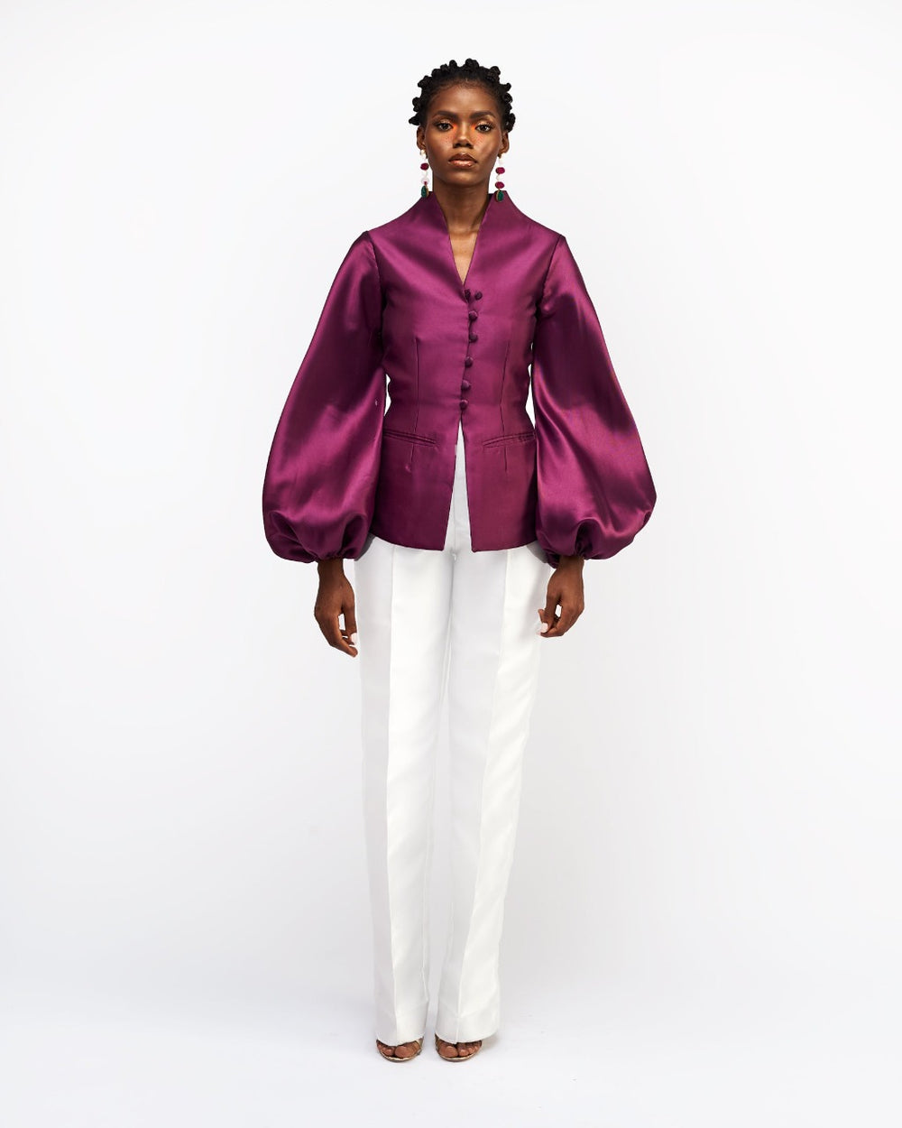 A model wearing aubergine colored silk satin jacket with white pants