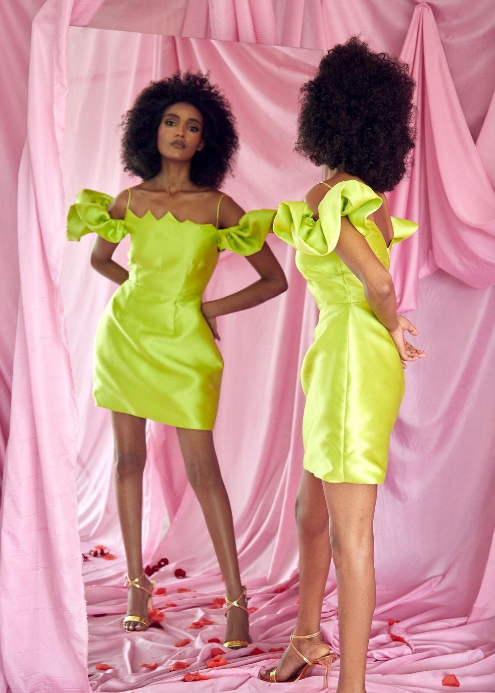 The back of a model wearing a Chartreuse dress with a strap and flare sleeve in front of a mirror