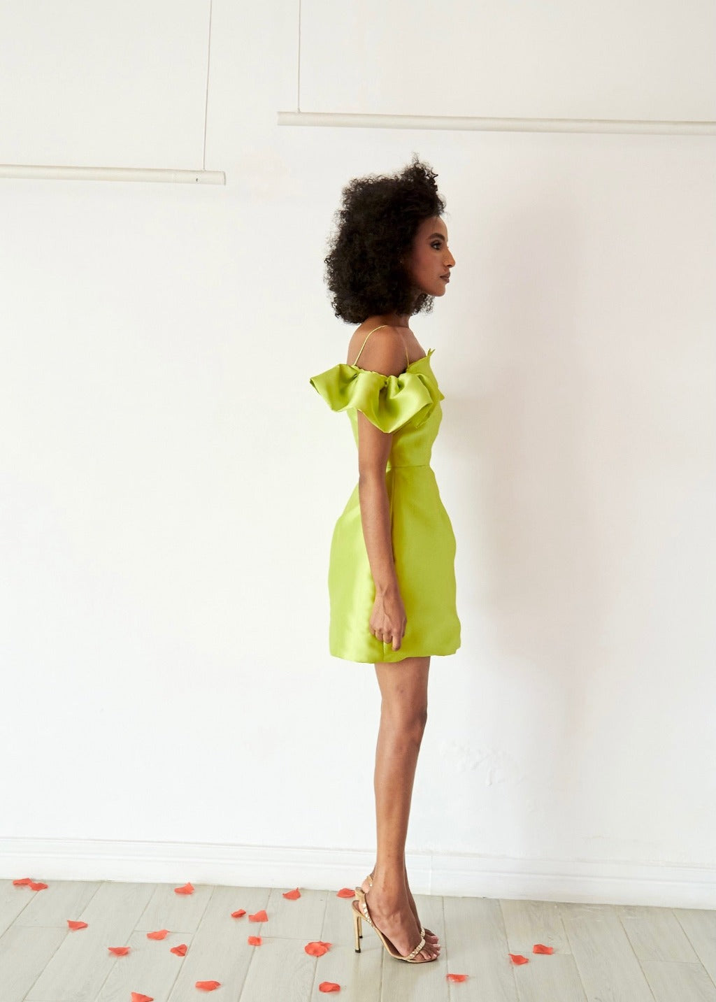 The side of a model wearing a Chartreuse dress with a strap and flare sleeve