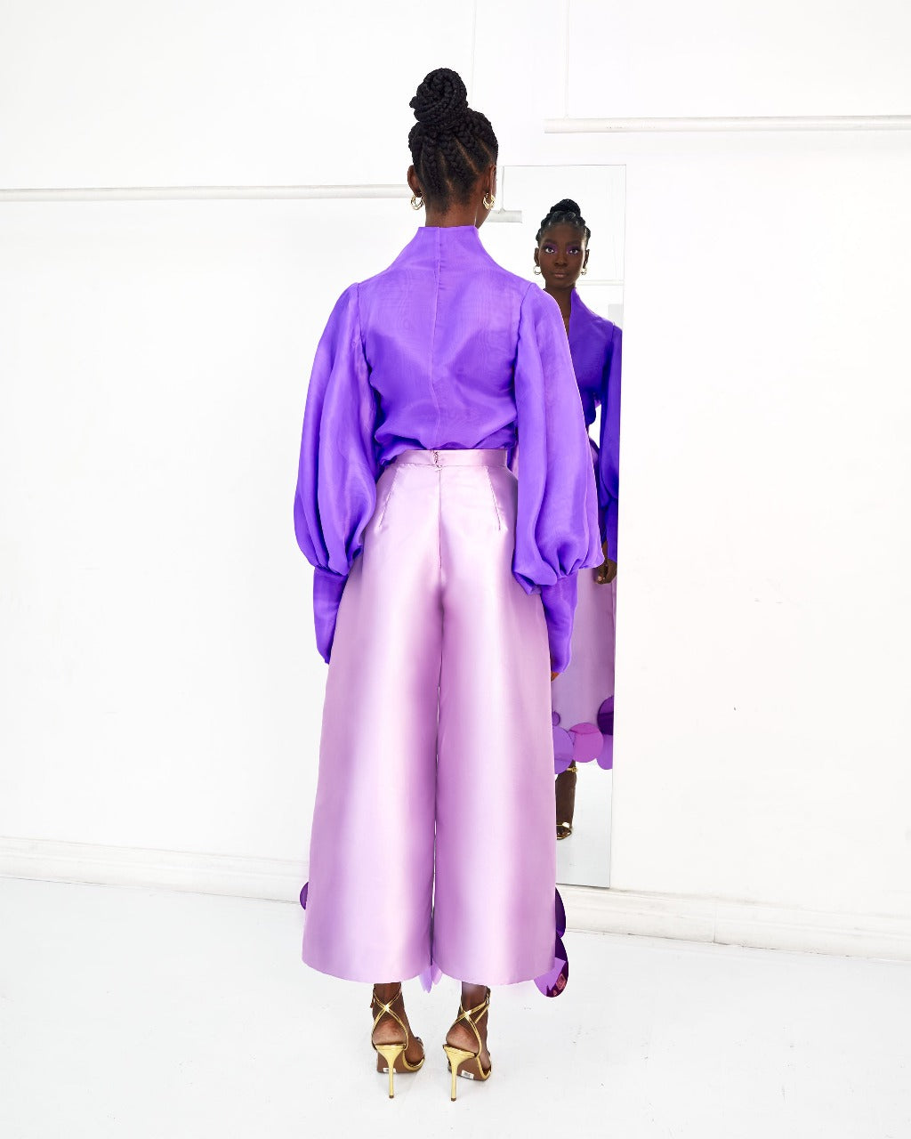 The back of a model wearing a Lilac top and a Lilac pants with sequins embellishment in a white room