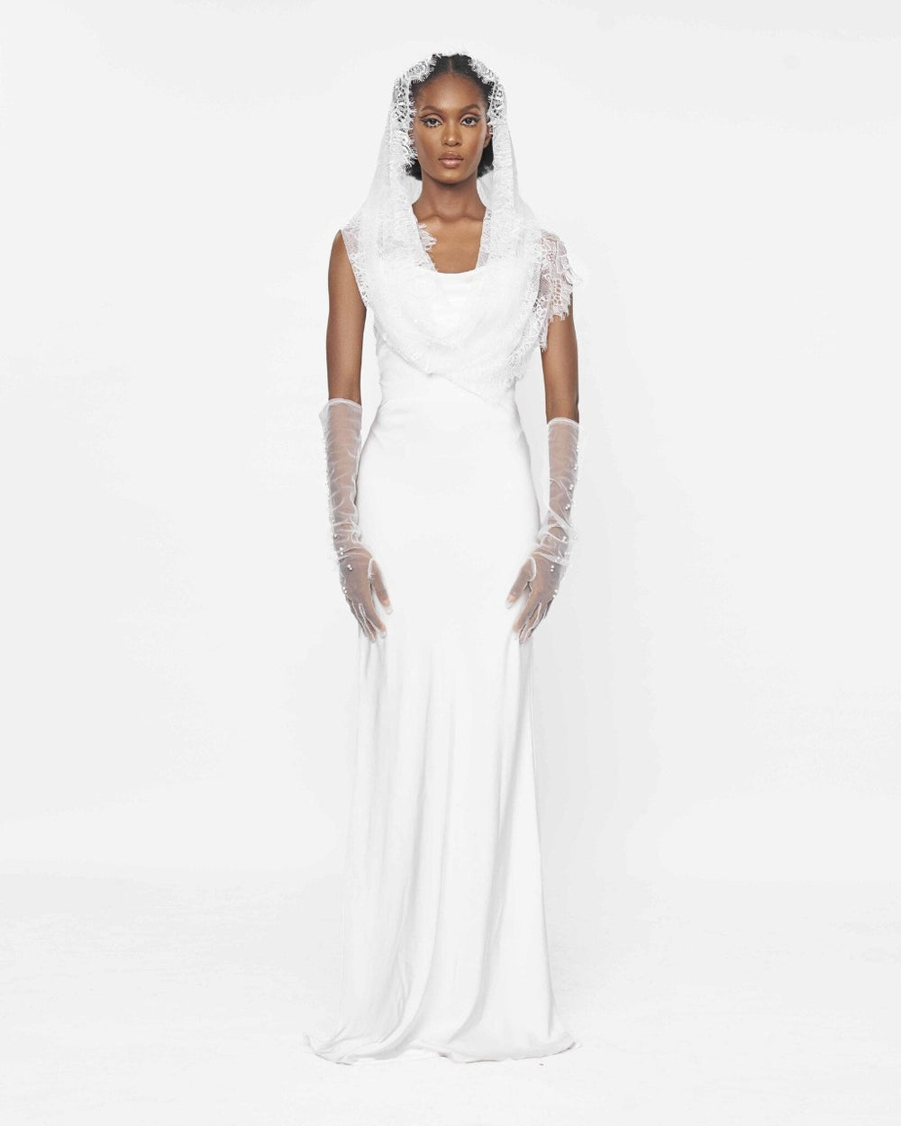 A model wearing a White slip dress and a lace veil over her head