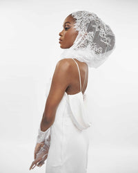 Close-up of the side of a model wearing a White slip dress and a lace veil over her head