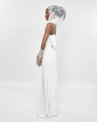 The side of a model wearing a White slip dress and a lace veil over her head