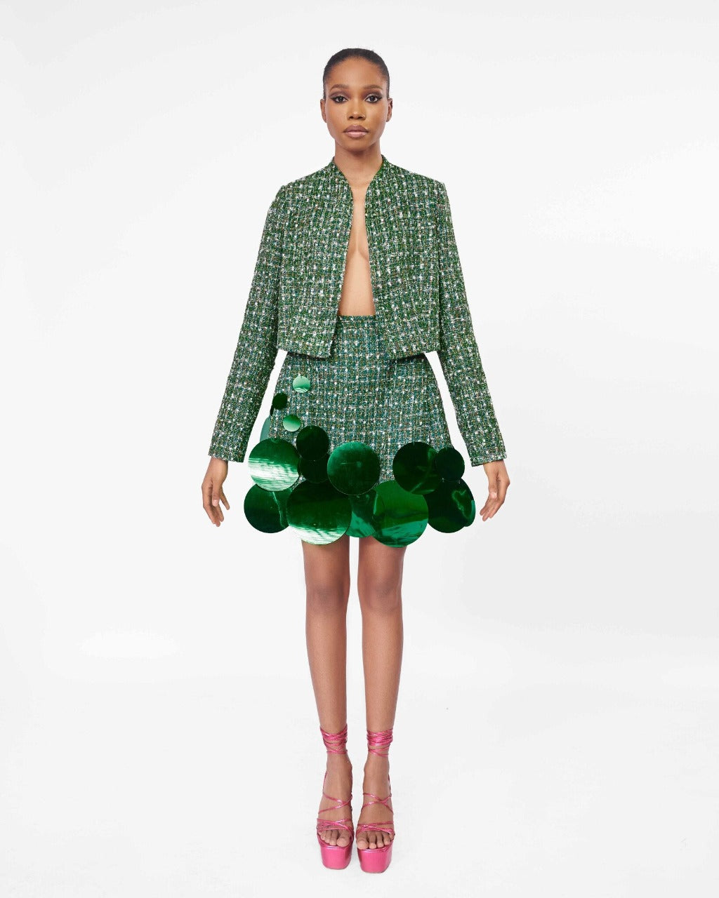 A model wearing a Green, long sleeve crop jacket and Green high waist mini skirt with sequins embellishment