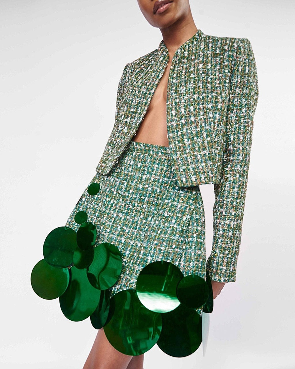 A model wearing a Green long sleeve crop jacket and Green high waist mini skirt with sequins embellishment