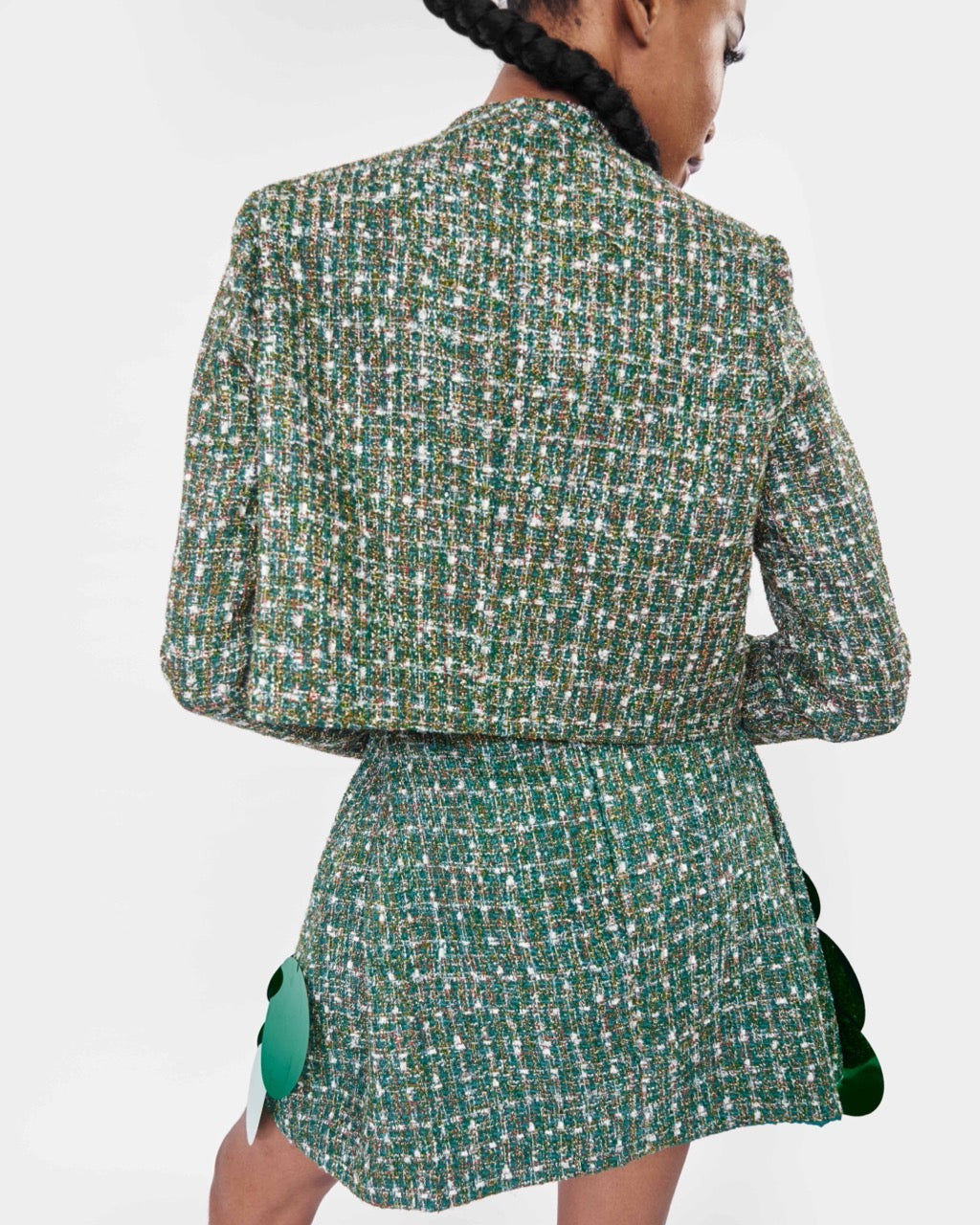 The back of a model wearing a Green long sleeve jacket and a Green mini skirt with sequins embellishment