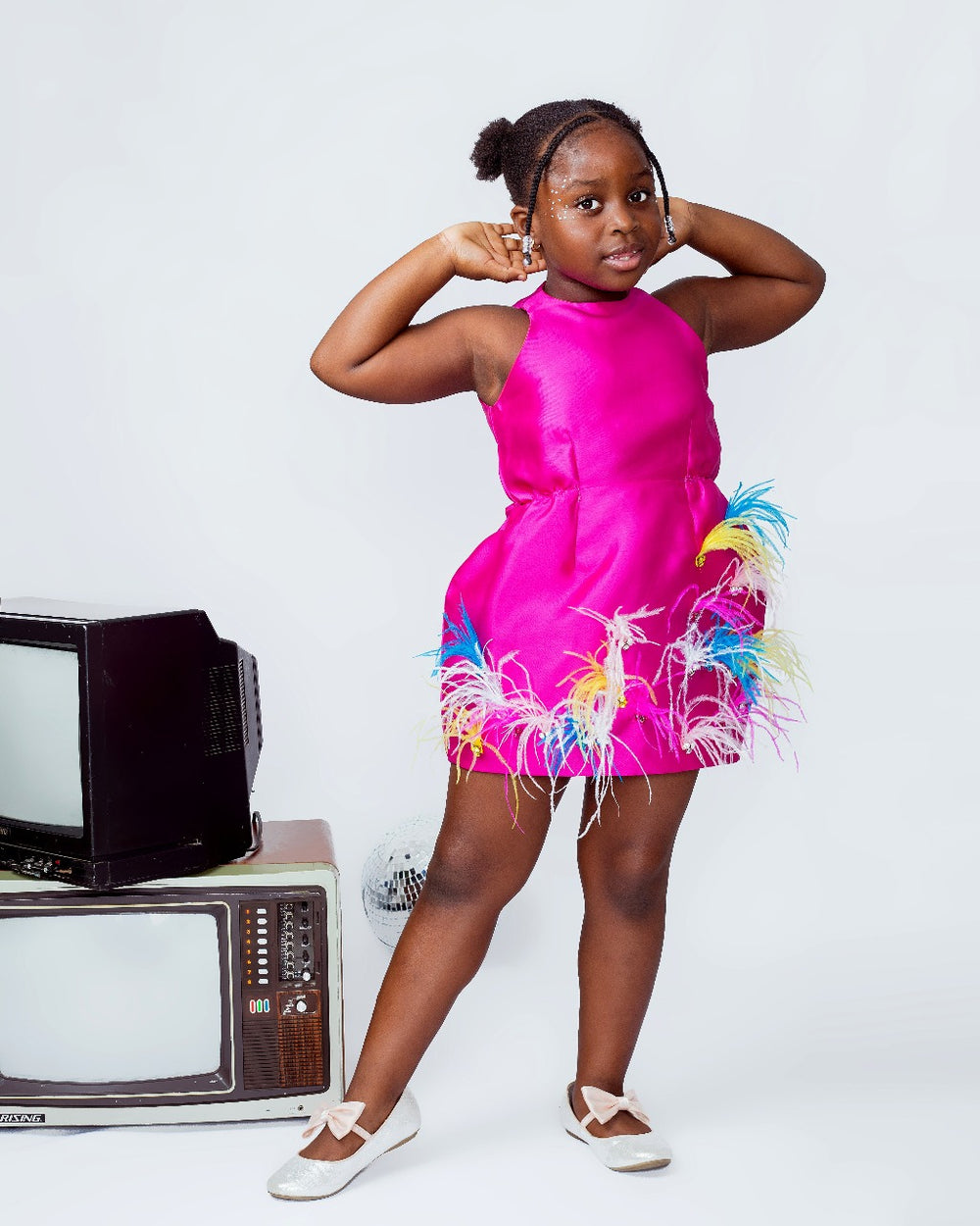 A kid model wearing a magenta dress with ostrich feathers 