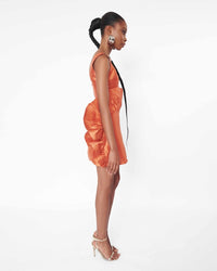 The side of a model wearing an Orange crop top and an Orange mini skirt with ruffles 