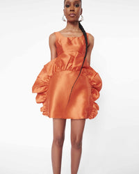 Close-up of a model wearing an Orange crop top and an Orange mini skirt with ruffles 