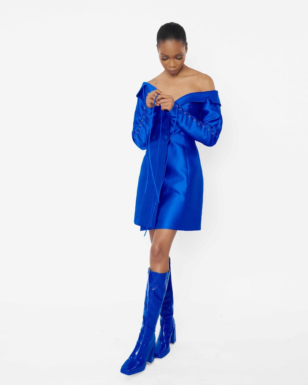 A model wearing a Blue structured asymmetric neckline jacket dress with a lacing sleeve detail 