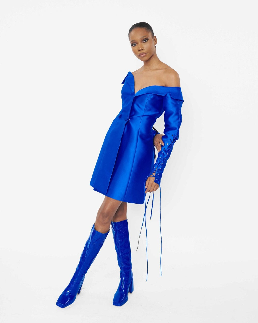 A model wearing a Blue structured asymmetric neckline jacket dress with a lacing sleeve detail 