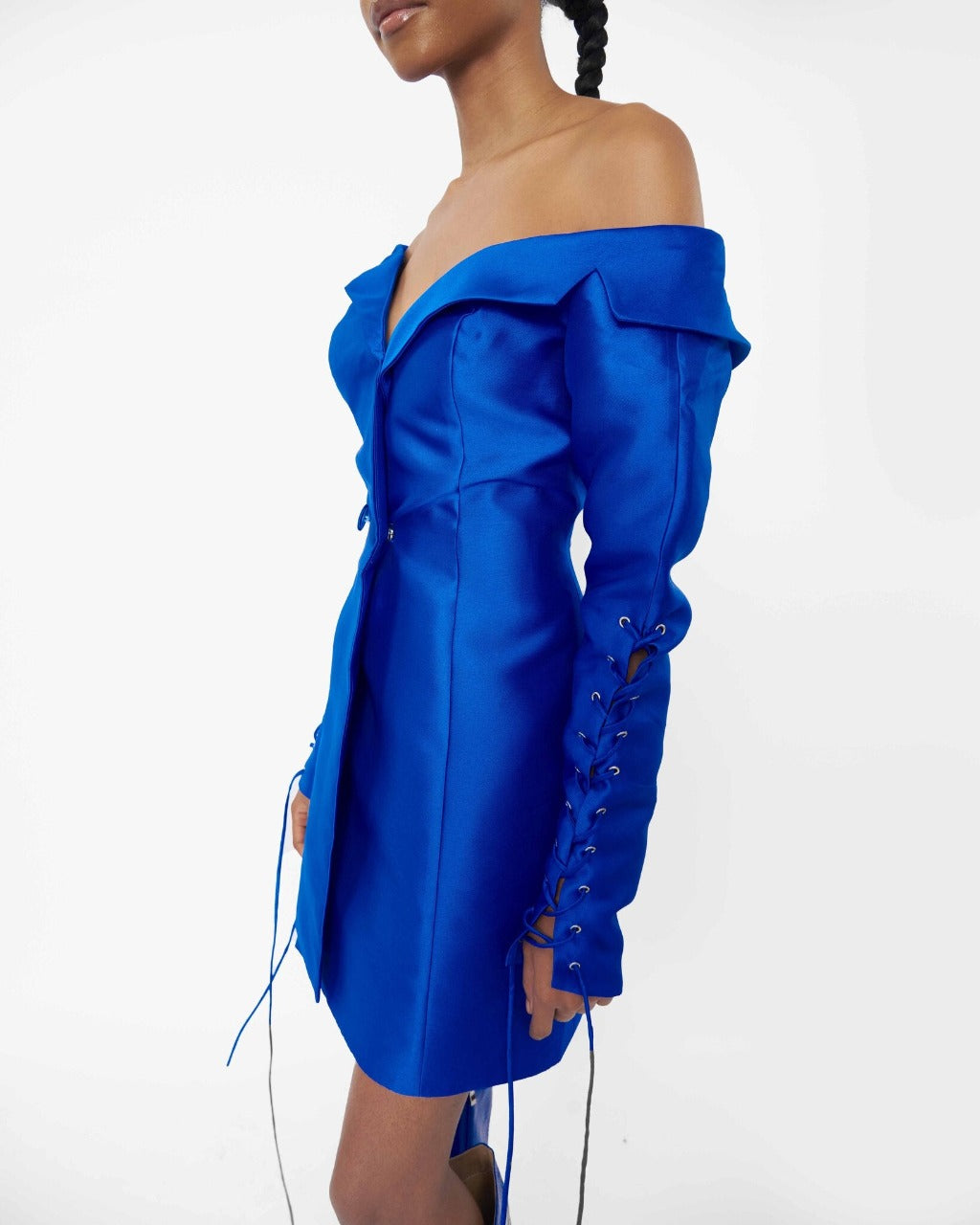 Close-up of a model wearing a Blue structured asymmetric neckline jacket dress with a lacing sleeve detail 