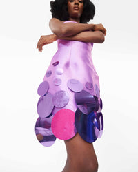Close-up of a model wearing a Lilac mini dress with a criss-cross neckline and sequins embellishment at the hem