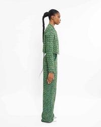 The side of a model wearing a Green jacket and sequins embellishment at the neckline and sleeve hem and a Green straight-cut pant