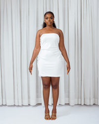 A model wearing a strapless White mini silk slip in front of white curtains 