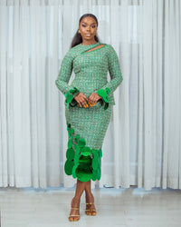 A model wearing a Green top with cut-out neckline detail and sequins embellishment at the neckline and sleeve hem and a Green midi skirt with sequins embellishment in front of white curtains