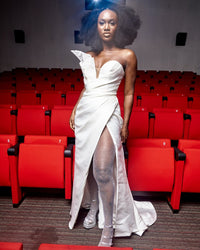 A model wearing a White asymmetric dress with thigh high slit in a movie theater
