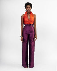 A model wearing purple silk satin pants with an orange top 