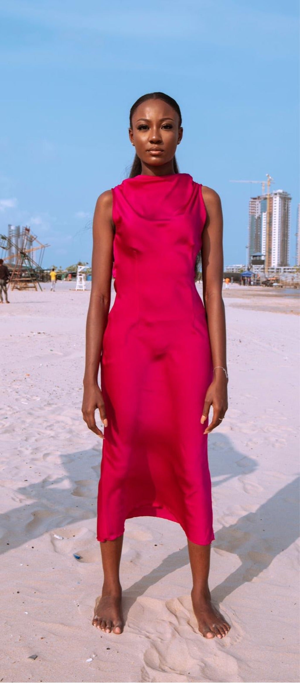 a model wearing a magenta dress on a beach